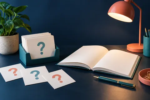 Cartes de questions devant un cahier ouvert sur un bureau